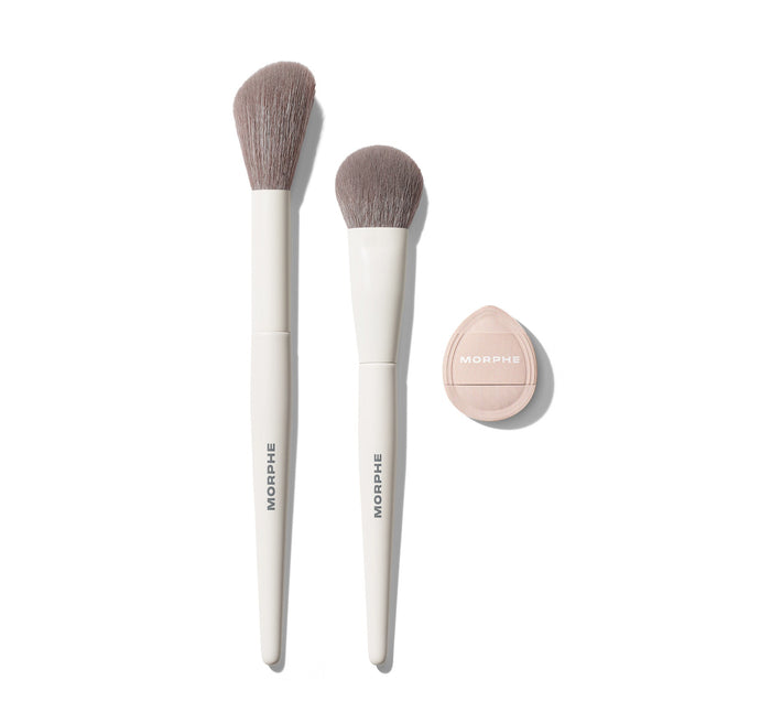 Morphe Blush Layering Tool Trio: two white MORPHE brushes with taupe bristles beside a nude-pink MORPHE compact sponge, shadow view.