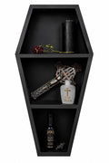 Black coffin-shaped shelf with decorative items including a bottle, cross, and rose.