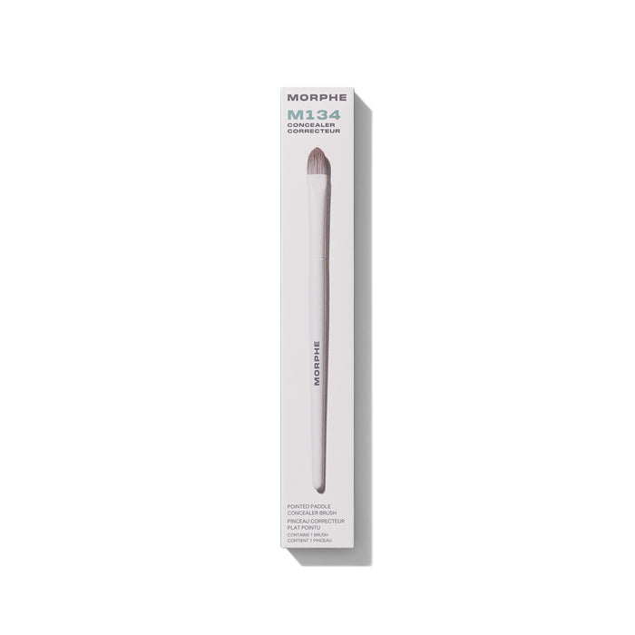 M134 Pointed Paddle Concealer Brush in white retail box. Embedded text: "MORPHE M134 CONCEALER CORRECTEUR POINTED PADDLE CONCEALER BRUSH PINCEAU CORRECTEUR PLAT POINTU CONTAINS 1 BRUSH / CONTIENT 1 PINCEAU"