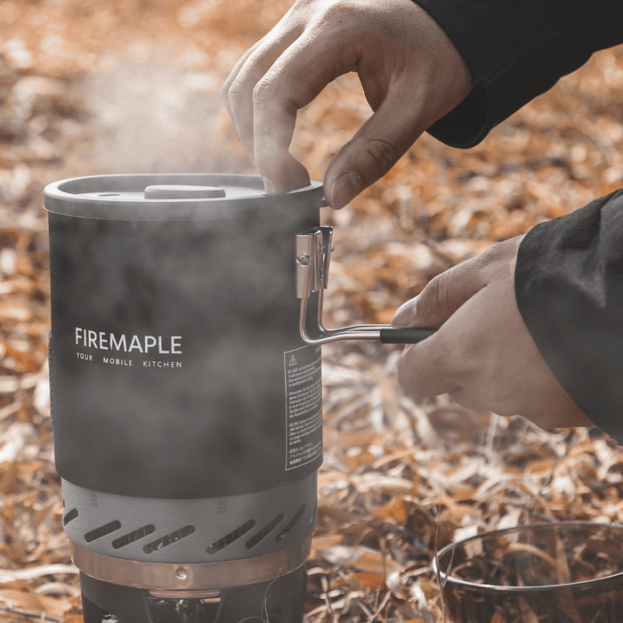Person using a Firemaple portable stove outdoors with leaves in the background#color_black-red